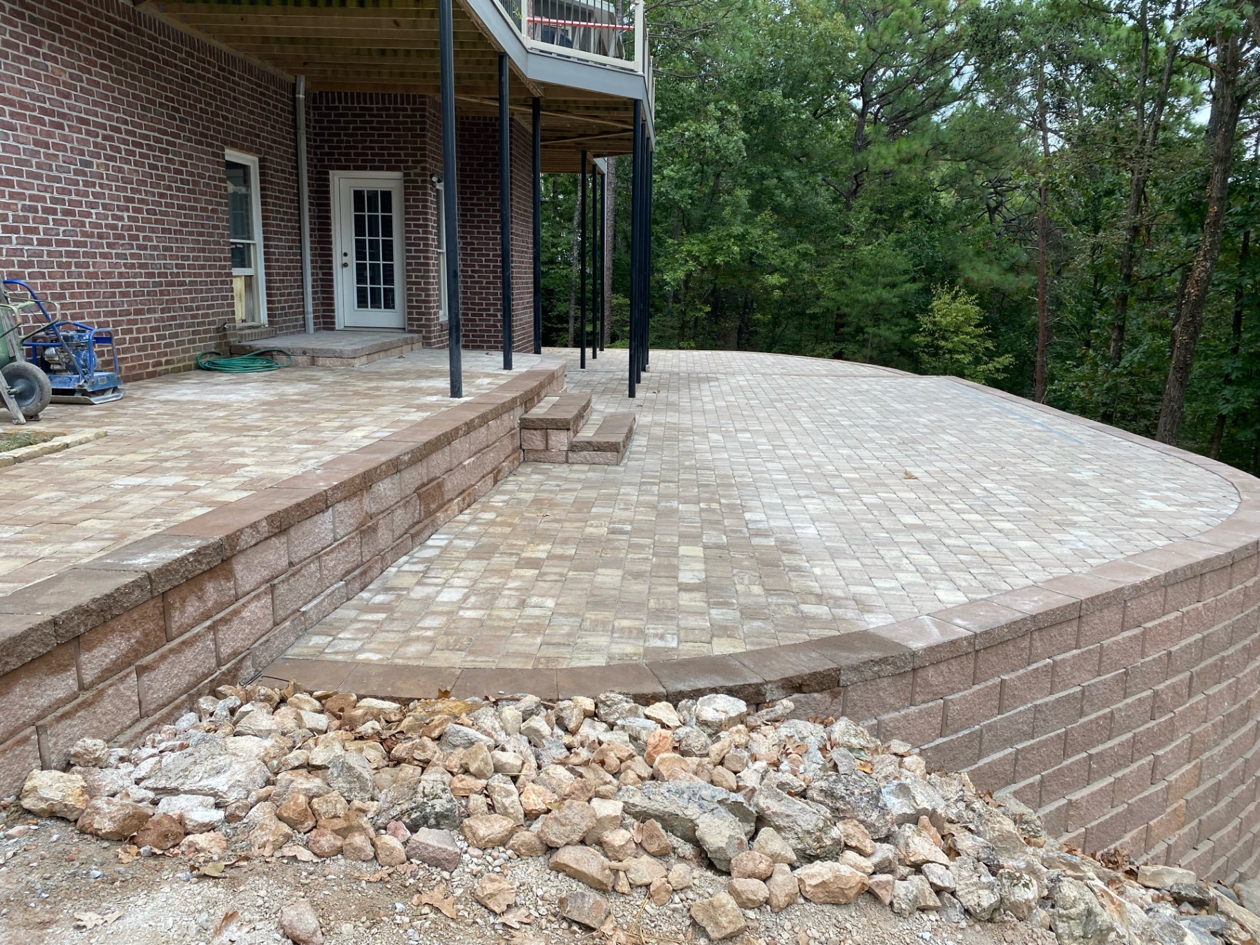 Large paver terrace supported by a retaining wall beside a home
